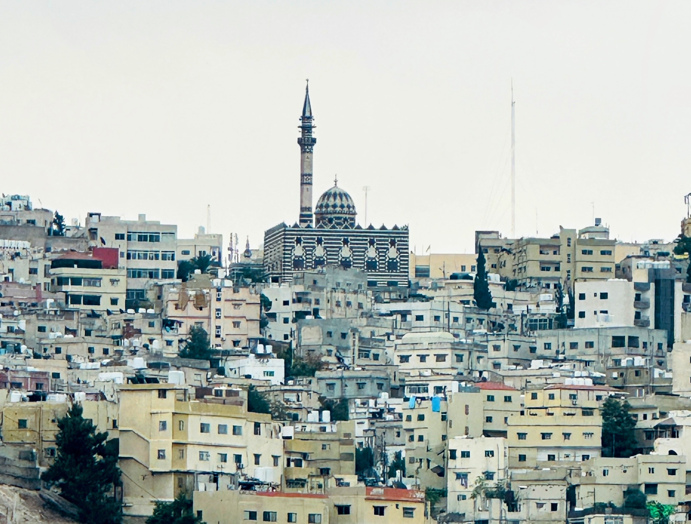 Vista panorâmica da cidade de Amã, na Jordânia, com uma mesquita ao fundo destacando-se entre os edifícios urbanos.
